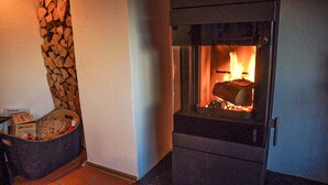 Una chimenea con pared de piedra y un cesto de leña.