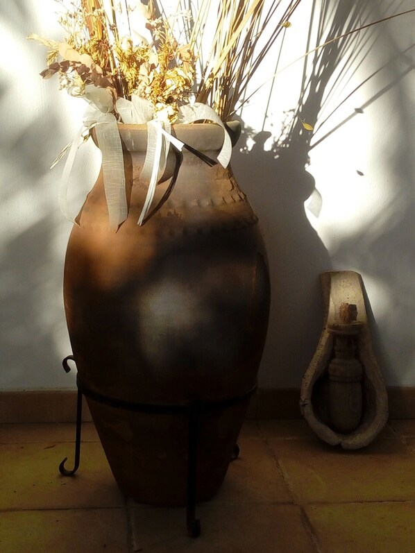 Un grand vase en céramique orné d’un ruban, placé à côté d’une petite cuvette de toilettes au style rustique.