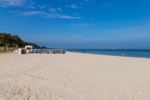 A beach with a row of beachside kiosks and a few people walking.