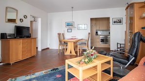 Ein kompakter Wohnbereich mit Essbereich, Küchenzeile und einer Sitzecke mit Fernseher und Schrank.