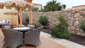 A patio with wicker furniture, a round table, and thatched umbrellas. - Romantic Villa Romeo with private pool, with stunning panoramic views of the (Costa Calma)