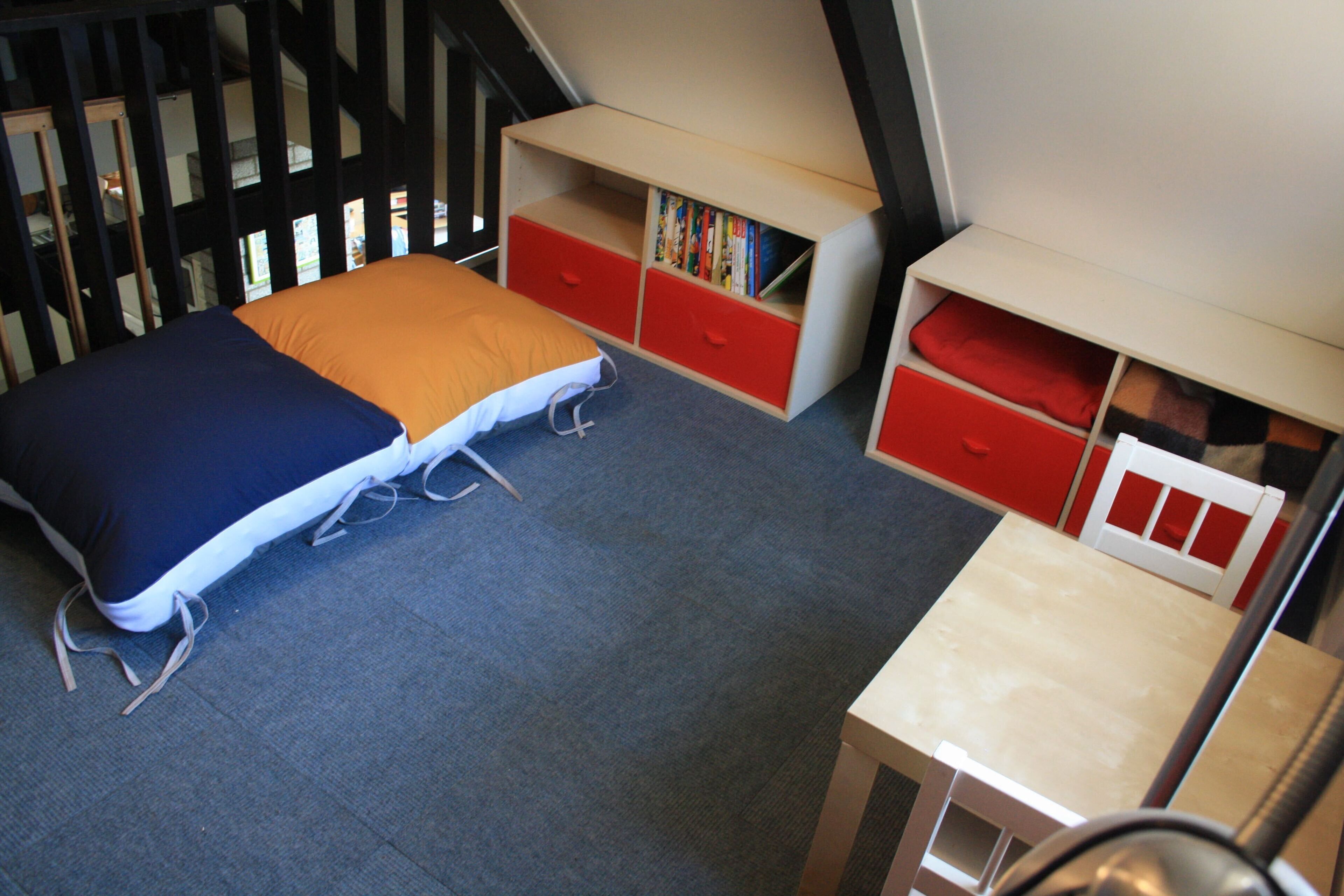 A compact room with a bed, a desk, and storage units.
