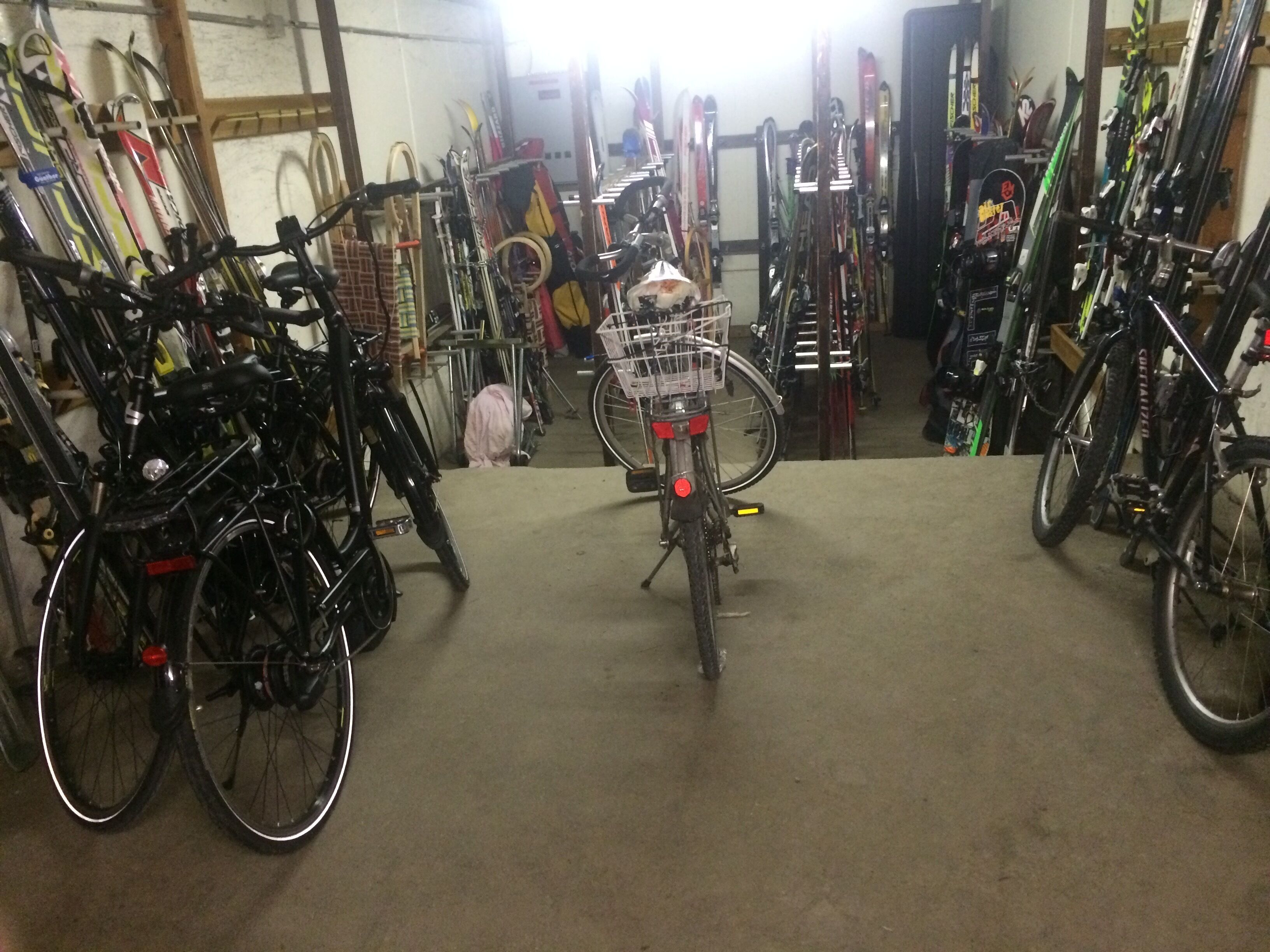 Un espace de stockage pour vélos contenant plusieurs vélos, dont l’un est équipé d’un panier.