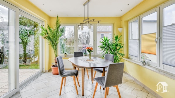 A dining area with a round table, four chairs, and potted plants. - Bright vacation apartment with 68sqm and south-facing terrace for max. 4 people (Lindau (Bodensee))