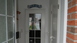 Ein Flur mit einer Glastür, einer schwarzen Matte und einem Schild darüber.