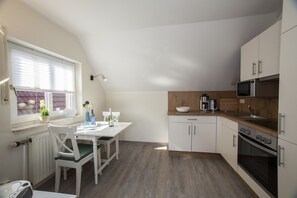 Une cuisine moderne avec des meubles blancs, un plan de travail en bois et un four à micro-ondes encastré.