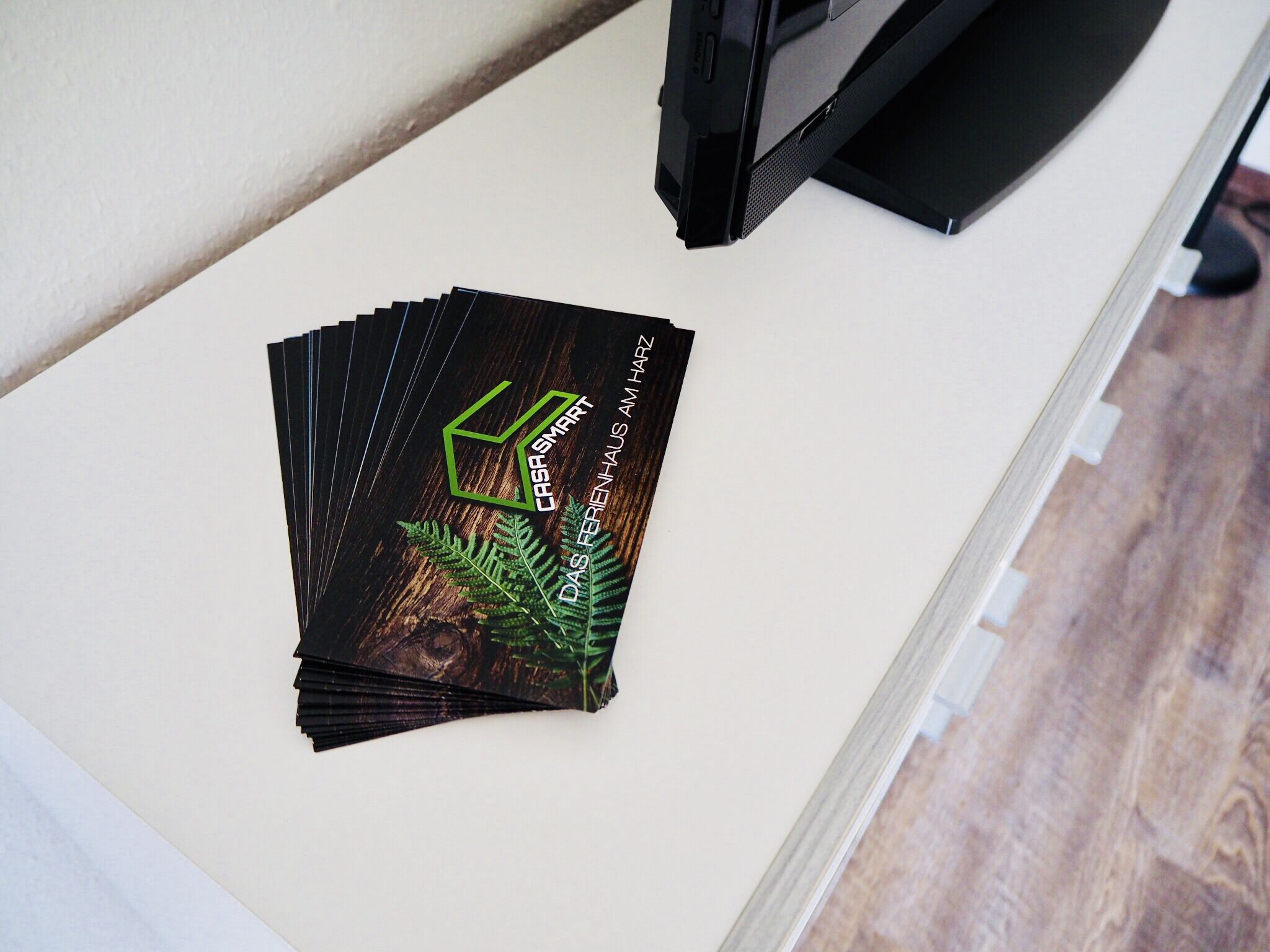 A stack of cards with a green logo and text on a white surface next to a television.