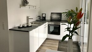A modern kitchen with white cabinets, a black countertop, a coffee maker, and a small oven.