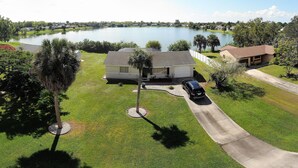 A residential area with a house, a driveway, and a lake in the background. - House with solar heated pool and lake view! (Port Charlotte)