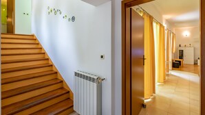 Portaat, joissa on puiset askelmat ja jotka johtavat ylätasanteelle, patteri ja käytävä, jossa on myös patteri ja ovi, joka johtaa toiseen huoneeseen.