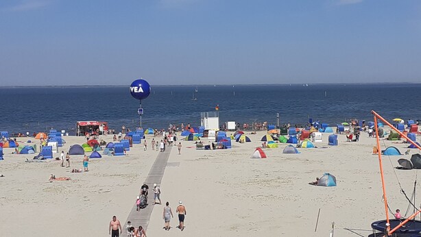 A beach with numerous tents and a large blue balloon with "VEA" on it. - Holiday house near the beach, child-friendly, high quality, Weber grill, WiFi free (Dornum)