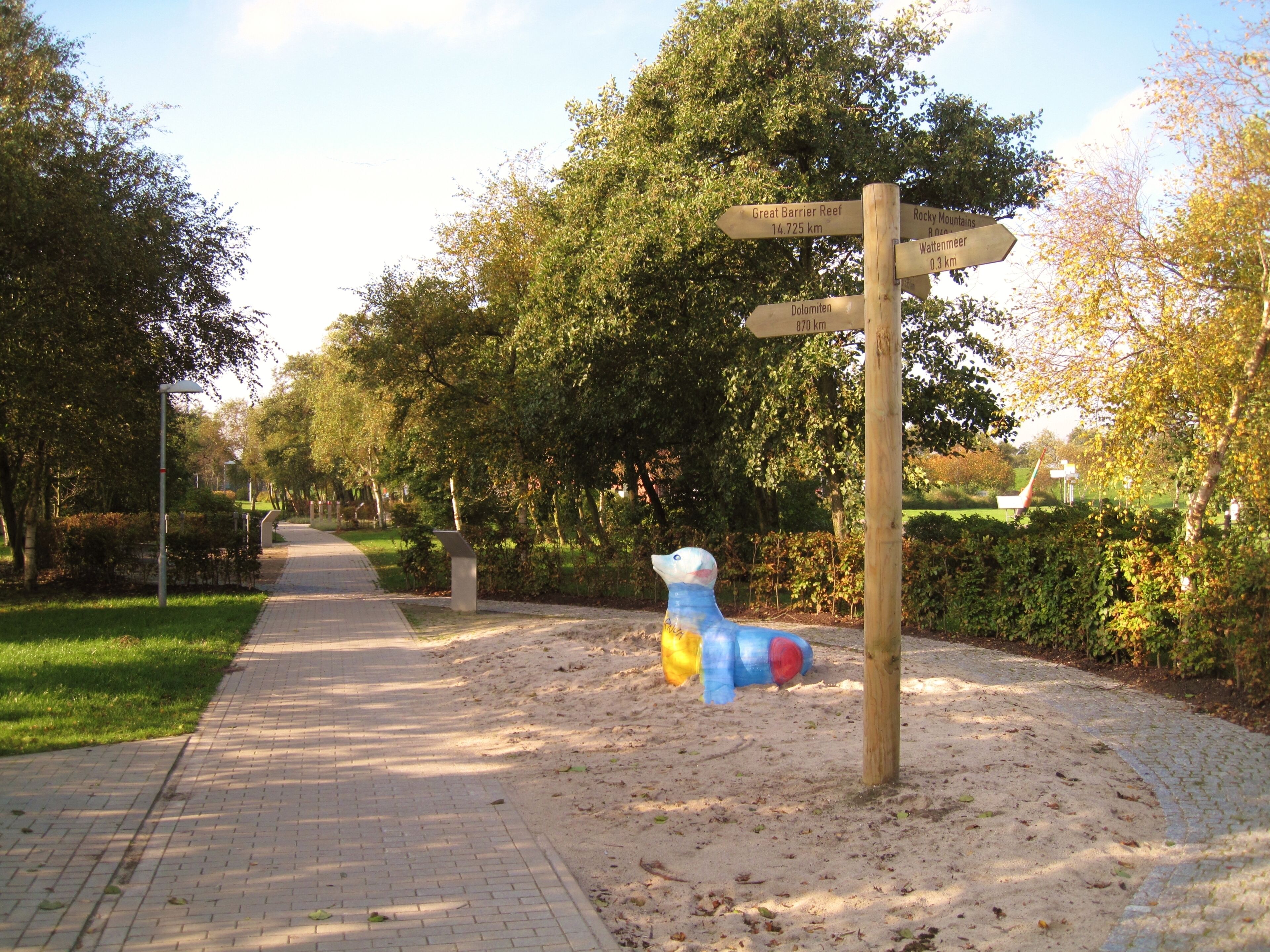 A pathway with directional signs and a sculpture of a bird.