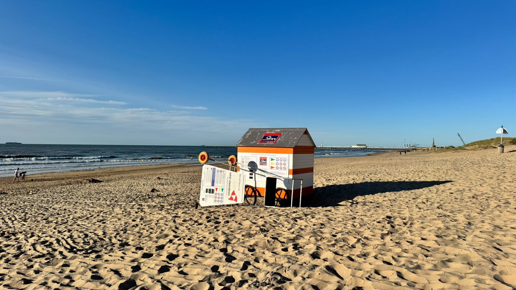 A beach with a lifeguard hut and a signboard.