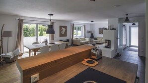 A modern kitchen with a central island, dining area with a table and chairs, and a living area with a sofa and a fireplace. - Tegernsee Chalet vacation homeexceptional (Gmund am Tegernsee)