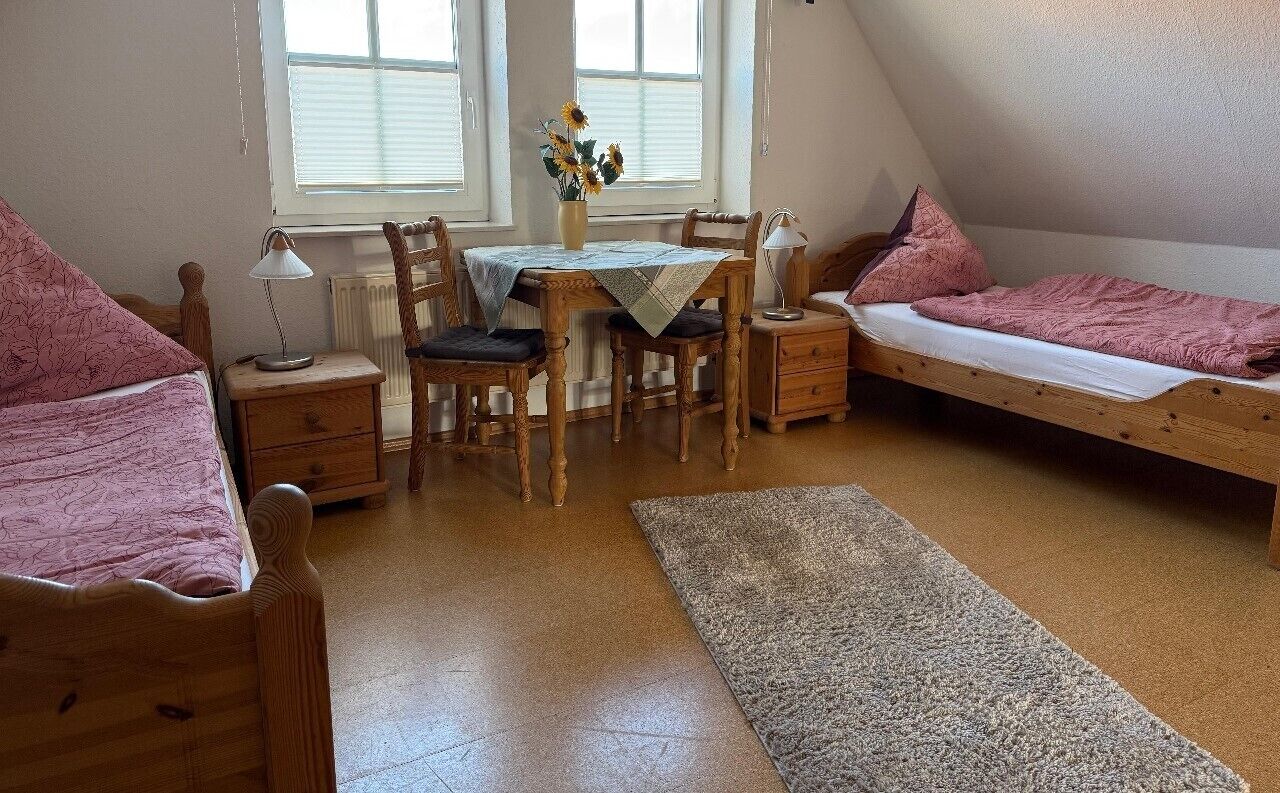 Una habitación con cama, escritorio, silla, mesa y ventana.
