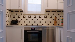 Una cocina compacta con armarios blancos, horno empotrado y lavavajillas.