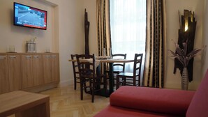 Un comedor con una mesa, sillas y un televisor en la pared mostrando una escena de carretera.