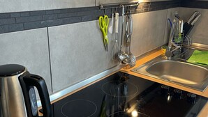 Una cocina moderna con cocina por inducción negra, pileta de acero inoxidable y alacenas de madera.