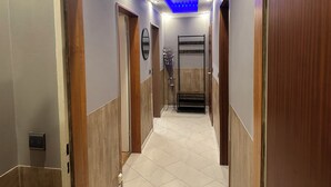 Un pasillo con puertas de madera, un espejo y un techo iluminado en azul.