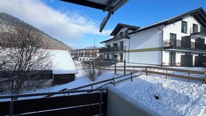 Zona residencial con suelo cubierto de nieve, una cerca de madera y casas con balcones.