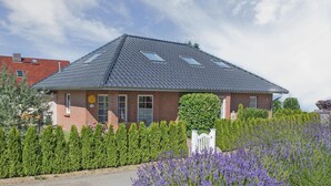 A two-story house with a sloped roof, a brick facade, and a small front porch. - 4-star holiday home with terrace, large garden, 3 bedrooms and 2 bathrooms (Seebad Heringsdorf)