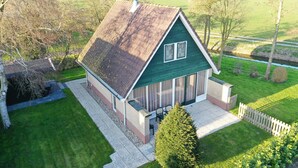 A green house with a sloped roof, a small porch, and a view of a green field. - A beautiful house with incredible views on a corner lot (Sint Maarten)