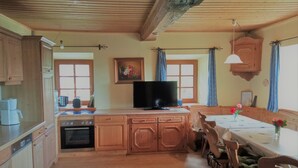 Una cocina de madera con una isla central, una mesa de comedor con sillas y un televisor.