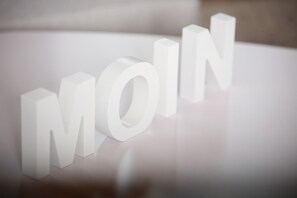 A 3D text "MOIN" on a reflective surface. - Schiller-Quartier 15 Apartment no. 3 (Bremerhaven)