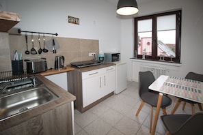 A compact kitchen with a coffee sign, a kettle, a toaster, and a dishwasher. There is a dining area with a table and chairs. - Schiller-Quartier 15 Apartment no. 3 (Bremerhaven)
