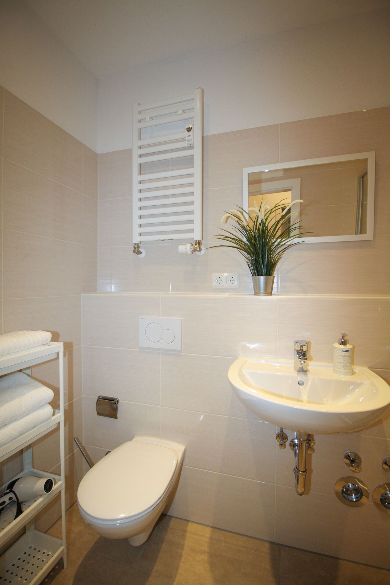 Une salle de bain équipée de toilettes, d’un lavabo, d’un porte-serviettes et d’un miroir.