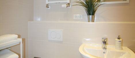 Une salle de bain équipée de toilettes, d’un lavabo, d’un porte-serviettes et d’un miroir.