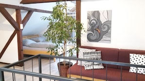 Ein Schlafzimmer im Loft-Stil mit einem Bett, einem roten Sofa, einer Topfpflanze und einem Wandbild.