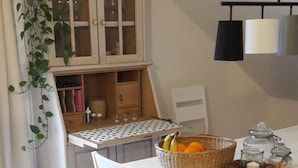 Ein Essbereich mit einem weißen Tisch, Stühlen und einer Obstschale.