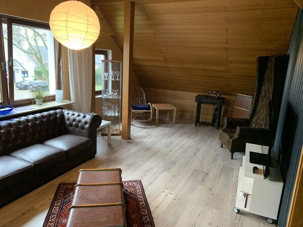 Une pièce confortable de style loft, avec un canapé en cuir, une petite table, un banc et une machine à coudre.