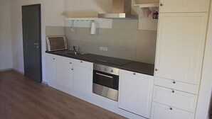 A compact kitchen with white cabinetry, a stainless steel oven, and a sink. - Holiday house with a private swimming pool and sauna in a rural idyll (Stepenitztal)