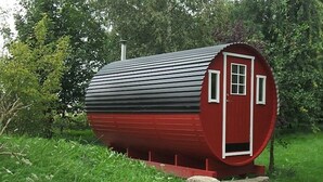 A cylindrical red building with a door and windows, surrounded by greenery. - Holiday house with a private swimming pool and sauna in a rural idyll (Stepenitztal)