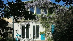 A two-story building with a covered patio area, a sliding glass door, and a wheelchair-accessible chair. - Holiday house with a private swimming pool and sauna in a rural idyll (Stepenitztal)