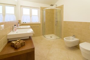 Une salle de bain équipée d’une douche, de deux lavabos, d’un bidet et de toilettes.