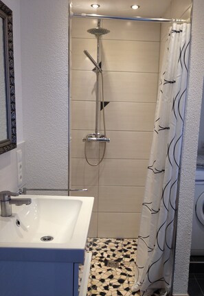 A bathroom with a white sink, a shower with a glass door, and a patterned floor.
