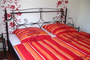 A bed with a metal frame and floral wall decoration.
