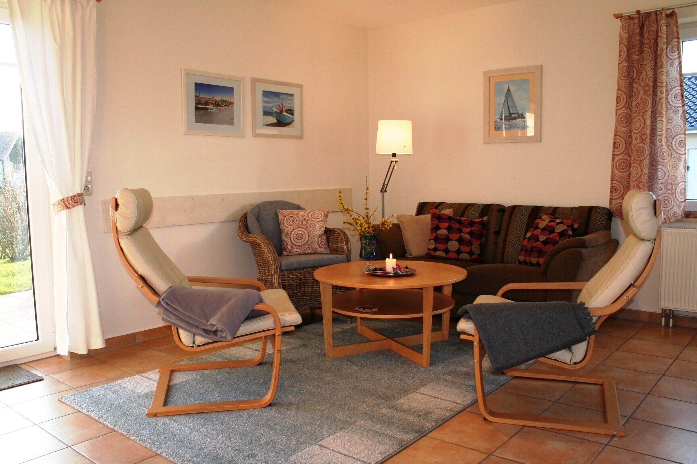 A living room with a sofa, two rocking chairs, a coffee table, and a lamp. There are three framed pictures on the wall.