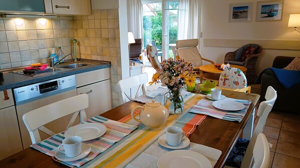 A modern kitchen with a Bosch oven, a dining area with a table set for two, and a view of the garden through the window.