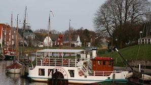 Ein Fluss mit mehreren vor Anker liegenden Booten, darunter ein markantes weißes Boot mit dem Namen 'CORDIA' auf der Seite.