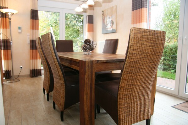 A dining area with a wooden table, wicker chairs, and a vase on the table.
