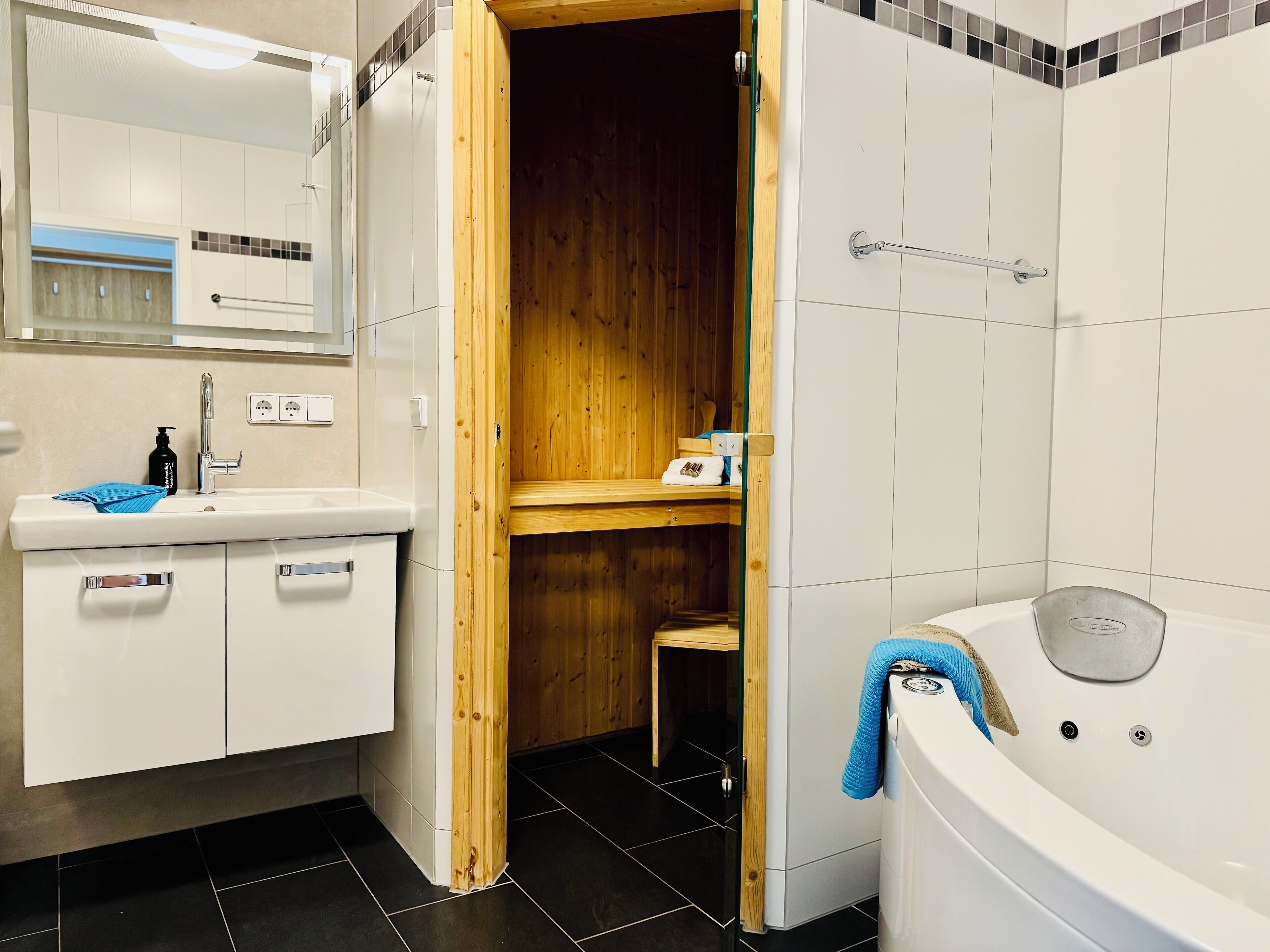 A modern bathroom with a wooden sauna, a white sink, and a bathtub.