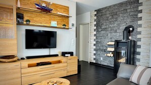 Een moderne woonkamer met een houten kast, een flatscreen televisie, een stenen muur, een open haard en een bank.