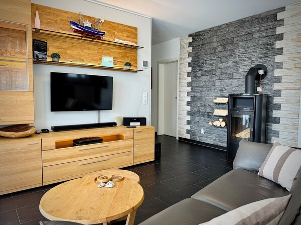 Una sala de estar moderna con un mueble de madera, un televisor de pantalla plana, una pared de piedra, una chimenea y un sofá.
