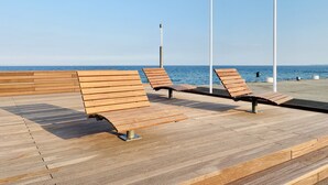 Een houten terras met banken met uitzicht op zee.