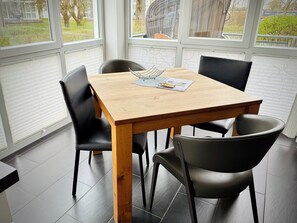 Un tavolo da pranzo con quattro sedie, un piano in legno e una finestra con persiane.