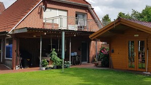 Una casa de ladrillo de dos pisos con balcón, un porche cubierto y una estructura de madera.